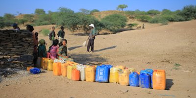 Community members, including children, line up to collect water, showcasing our water access initiatives